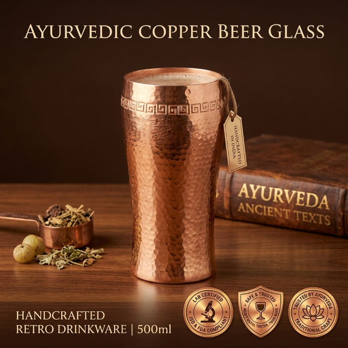 Copper beer glass with Ayurvedic theme on a wooden surface